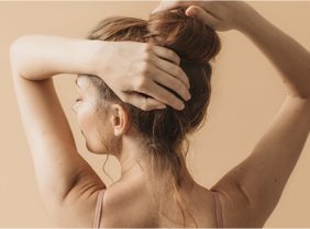 Lady putting hair in bun from behind