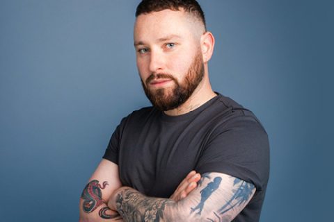 blog post image of a male with tattoo on arms on blue background